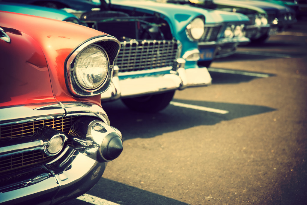 A close up of headlights and bumpers of vintage cars with flawless paint