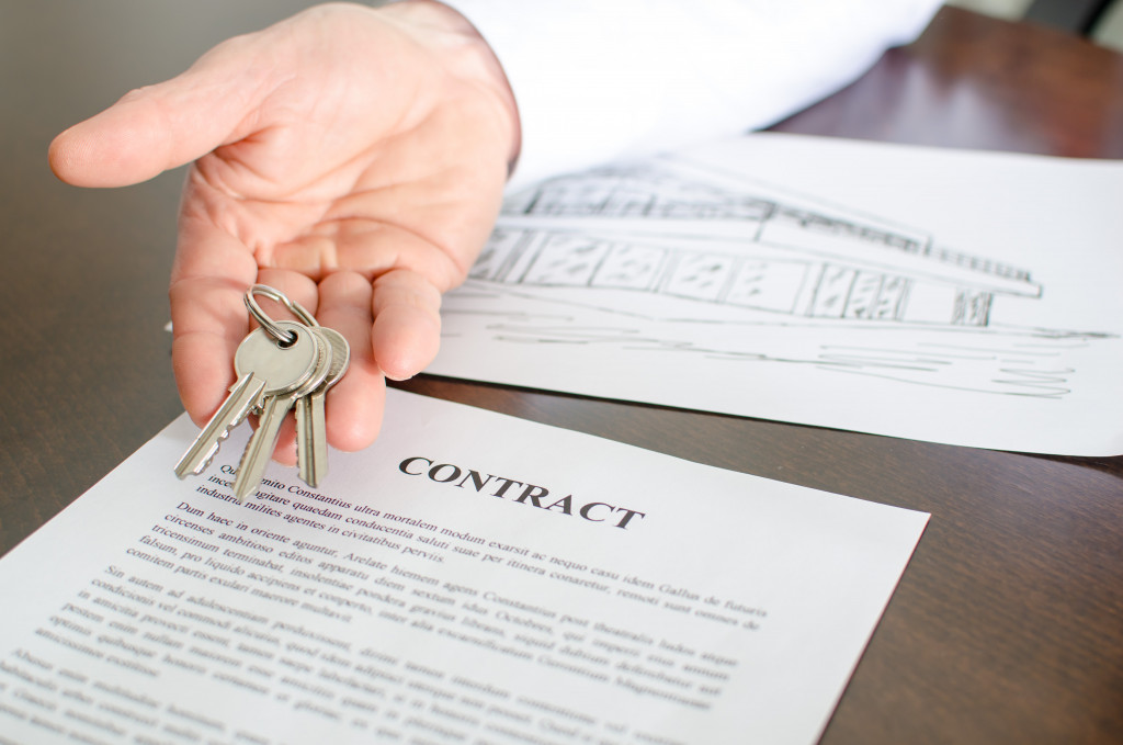 a hand holding a set of keys on top of a contract