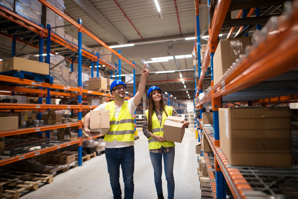 A male warehouse personnel pointing at ceiling with assistant