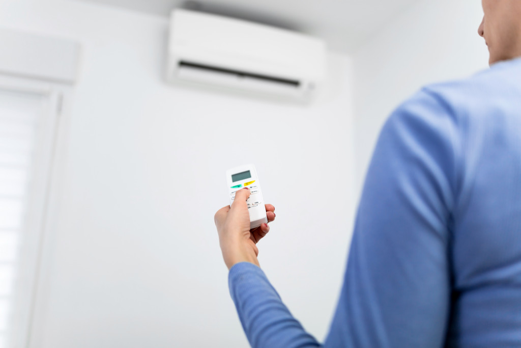 A woman holding the air conditioner remote
